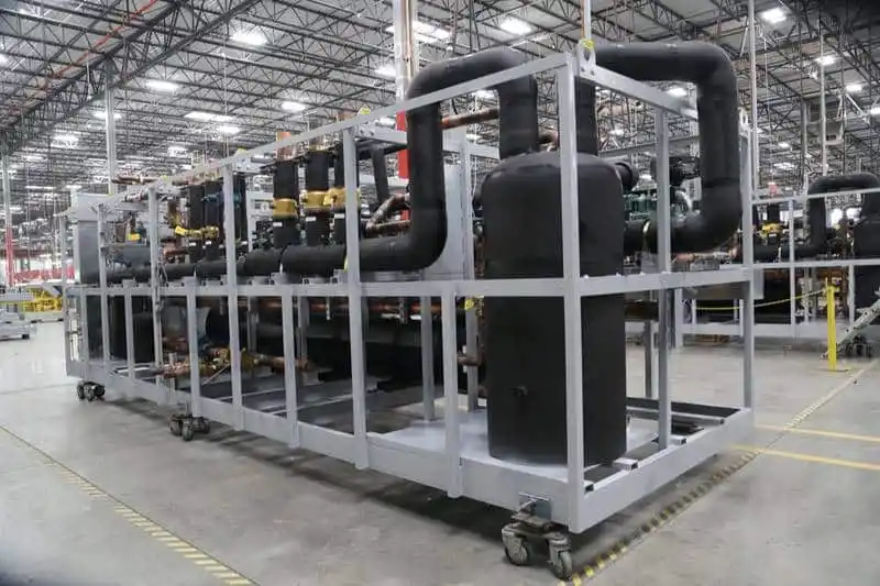 Large industrial refrigeration system under maintenance in a factory setting, showcasing black insulated pipes and metal frame structure for refrigeration repair services.