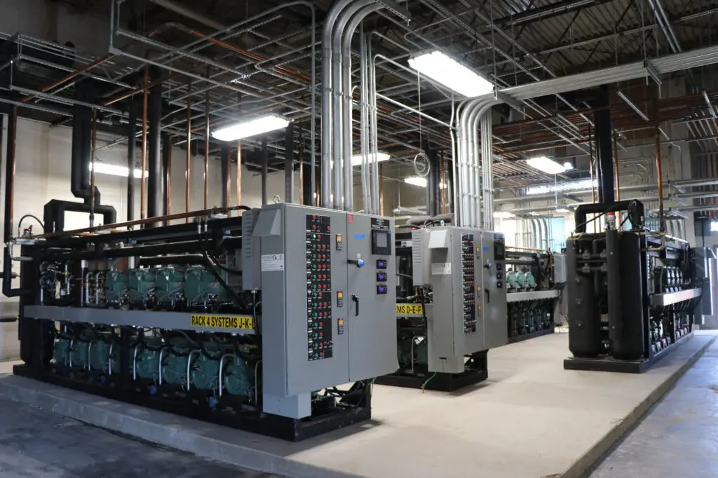 Large-scale commercial refrigeration system with control panels and compressors, highlighting routine Refrigeration Maintenance for industrial facilities